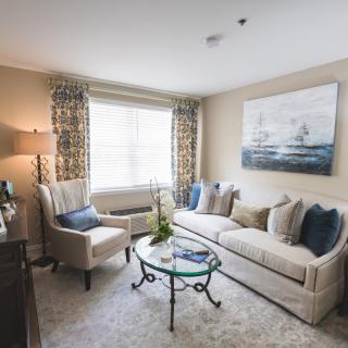 A cozy and elegantly decorated living room with a sofa, armchair, coffee table, and large window.