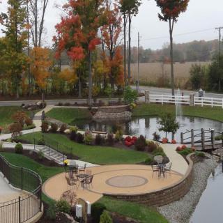 A beautifully landscaped garden featuring a pond, walkways, and autumn-colored trees.