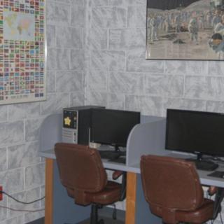 A small office space with two workstations, each equipped with a monitor and chair, and decorated with wall art.