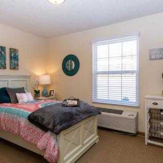 A cozy, well-decorated bedroom with a colorful bedspread and ambient lighting.