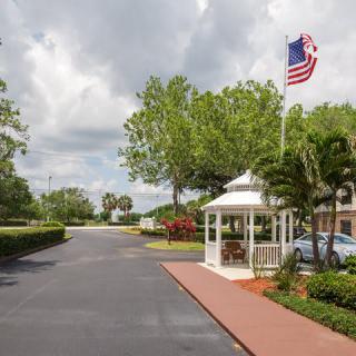 A small gazebo next to a road with an American flag and trees under an overcast sky.