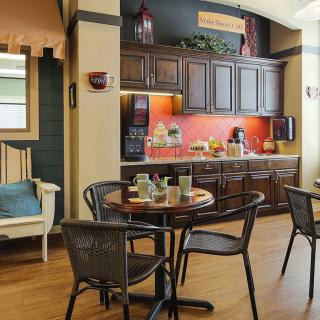 A cozy kitchen and dining area featuring wooden cabinets, a round table with chairs, and warm decor.