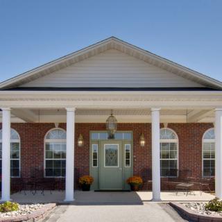 Front entrance of a brick building with columns and a green door.