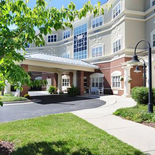 A modern building entrance with well-maintained landscaping and a sidewalk under a clear blue sky.