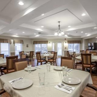 A spacious and well-lit dining room with neatly arranged tables and chairs, ready for guests.
