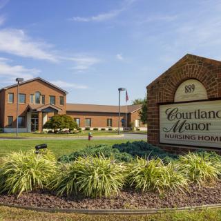 A view of Courtland Manor with its sign and surrounding greenery.