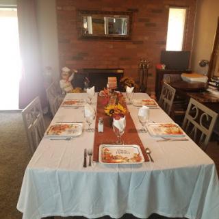 A beautifully set dining table ready for a meal, featuring a white tablecloth and a rustic wooden centerpiece.
