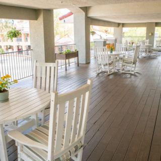 A spacious patio with wooden tables and chairs, enhanced by potted plants.