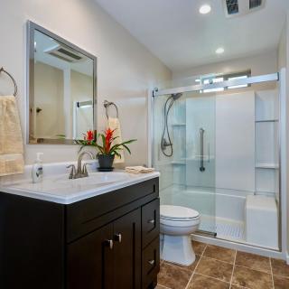A modern bathroom with a walk-in shower, vanity with sink, and large mirror.