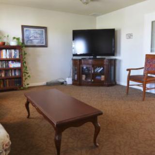 A cozy living room with a television, coffee table, and bookshelf.