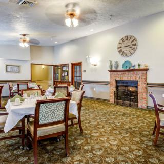 A cozy dining room with a warm fireplace and neatly set tables.