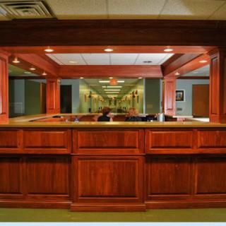 A wooden reception desk in a well-lit office lobby.
