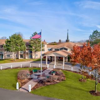 A picturesque building with an American flag, surrounded by landscaped gardens and trees in autumn.