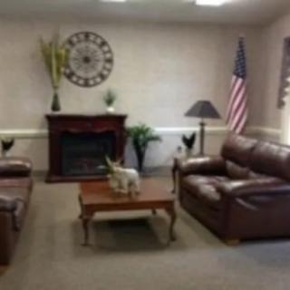 A cozy living room with leather sofas and a fireplace, accented by a decorative clock and flag.