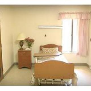 A simple bedroom with a single bed, nightstand, and window.