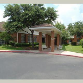 A building entrance with a covered walkway and surrounding greenery.