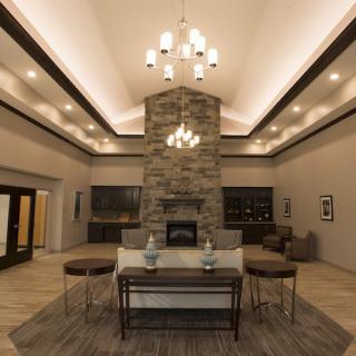 A modern living room with a central stone fireplace and stylish chandelier.