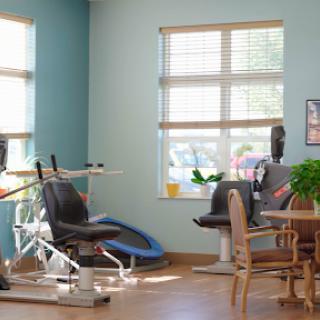 A well-lit rehabilitation room featuring exercise equipment and a cozy seating area.