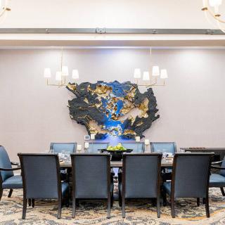 A modern conference room featuring a long table, upholstered chairs, and contemporary wall art.