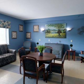 A cozy living room with blue walls, featuring a table and chairs, couch, and decorative artwork.