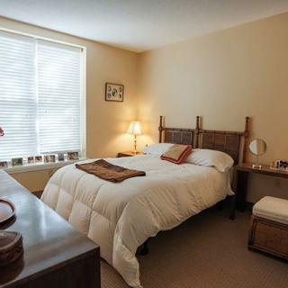 A cozy bedroom with a neatly made bed, nightstands, and soft lighting.