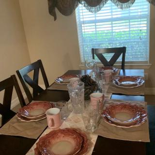 A dining table set for a meal with plates, glasses, and placemats.