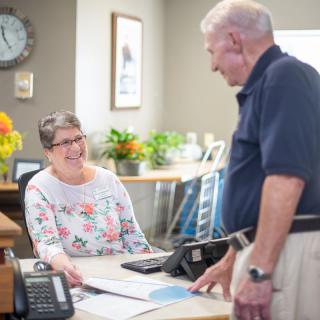 Two people engaged in a friendly conversation at an office desk.