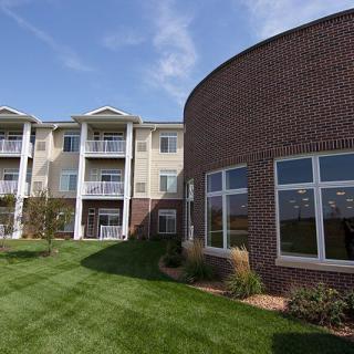 A modern apartment complex with a well-maintained lawn and brick exterior.
