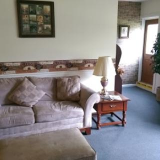 A cozy living room featuring a comfortable sofa, a lamp, and a welcoming entrance.