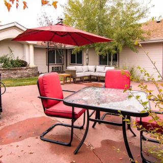A cozy backyard patio with red-cushioned seating and a large red umbrella.