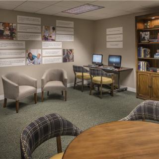 A cozy office space with computers, chairs, and a bookshelf.