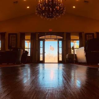 A warm and inviting lobby space with elegant lighting, showcasing a wooden floor and large doors that let in natural light.