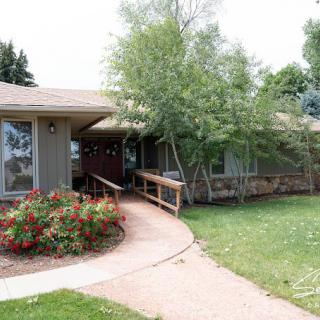 A house with a landscaped front yard featuring a pathway, trees, and flower beds.