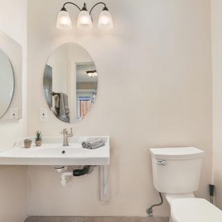 A clean and modern bathroom with a sink, oval mirror, and toilet.