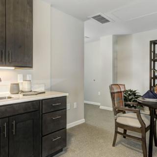 A modern kitchen and dining area featuring dark cabinets and elegant furniture.