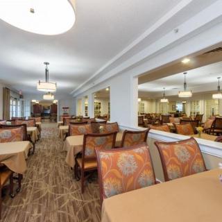 A spacious dining area with neatly arranged tables and chairs, featuring elegant lighting and decor.