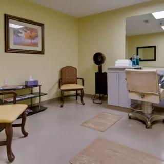 A cozy salon interior with chairs, a mirror, and hair styling equipment.
