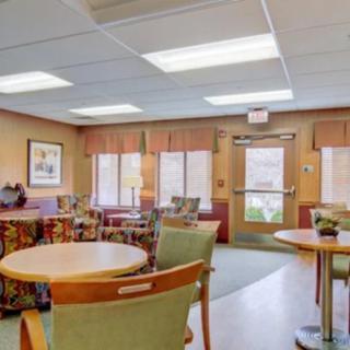 A cozy waiting room with tables and chairs, well-lit by ceiling lights and natural light from windows.