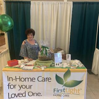 A representative at the FirstLight Home Care booth, promoting in-home care services for loved ones.