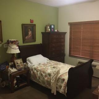 Cozy bedroom with a wooden bed and dresser, decorated with paintings and picture frames.