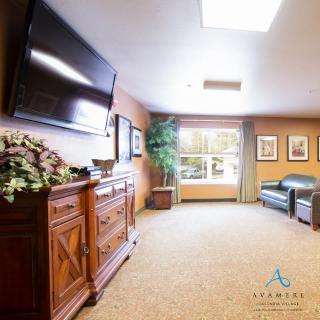 A cozy living room with a television, sofa, and large window allowing natural light.