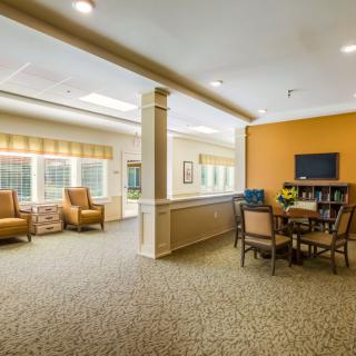 A cozy living space with comfortable seating, a table with chairs, and ample natural light through large windows.