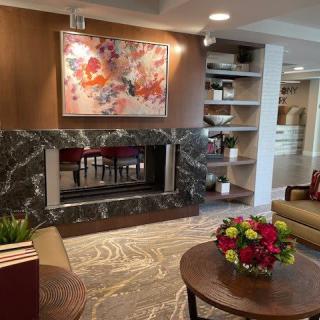 A modern living room with a fireplace, abstract artwork, and neatly arranged shelves.