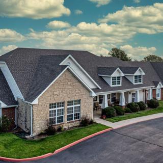 A suburban residential building with a stone facade and a cloudy sky background.