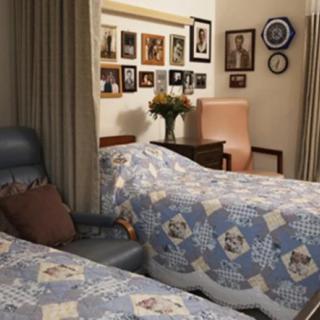 A cozy bedroom with twin beds adorned with patterned quilts, surrounded by a gallery of photo frames and decorative elements.