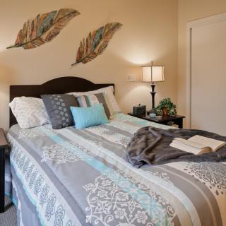 A cozy bedroom with a neatly made bed, decorative pillows, and wall art above the headboard.