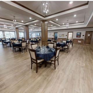 A spacious dining area with neatly arranged tables and chairs, illuminated by elegant chandeliers.