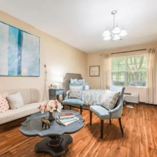 A cozy living room with modern furniture, featuring a comfortable sofa, chairs, and a coffee table on wood flooring.