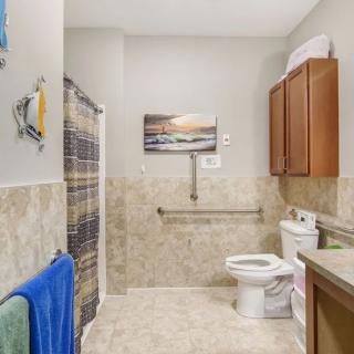 A modern bathroom with a shower, toilet, and cabinets, decorated with towels and artwork.