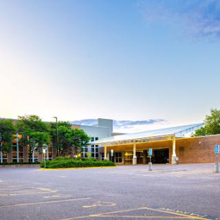 A modern architectural structure with landscaped surroundings, featuring a clear sky.